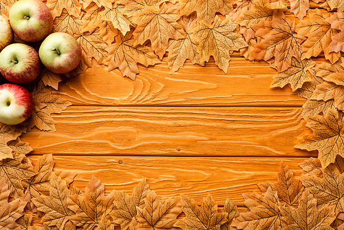 top view of ripe apples and autumnal foliage on wooden background