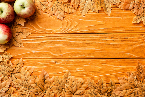 top view of ripe apples and autumnal foliage on wooden background