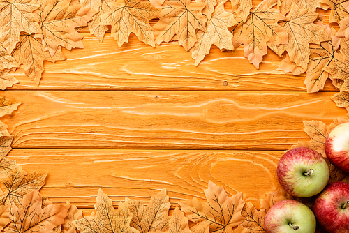 top view of ripe apples and autumnal foliage on wooden background