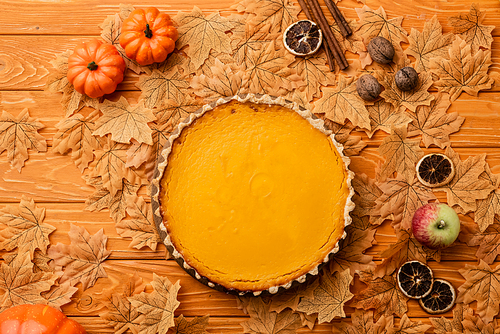 top view of pumpkin pie with autumnal decoration on wooden background