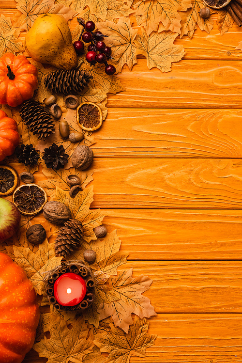 top view of burning candle with autumnal decoration on wooden background