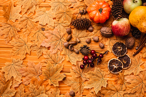 top view of autumnal decoration and food on golden foliage on wooden background