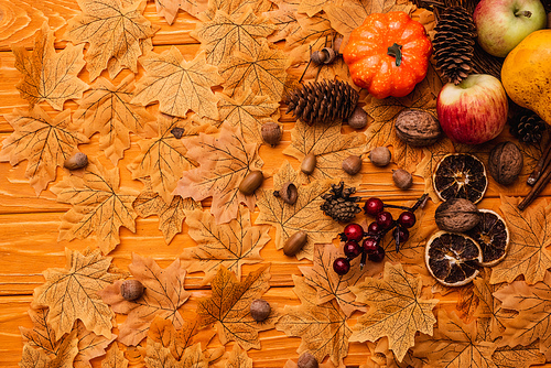 top view of autumnal decoration and food on golden foliage on wooden background