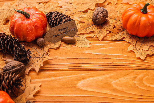 pumpkins, autumnal decoration and happy thanksgiving card on wooden background