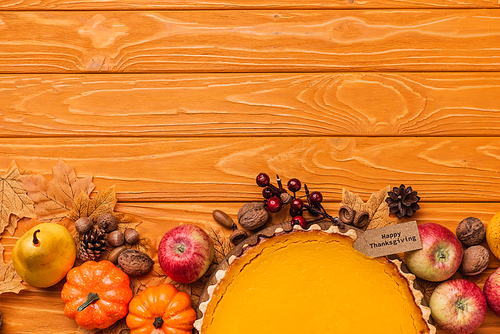 top view of thanksgiving pumpkin pie with autumnal decoration on wooden background