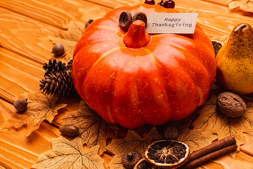 pumpkin with autumnal decoration and happy thanksgiving card on wooden background