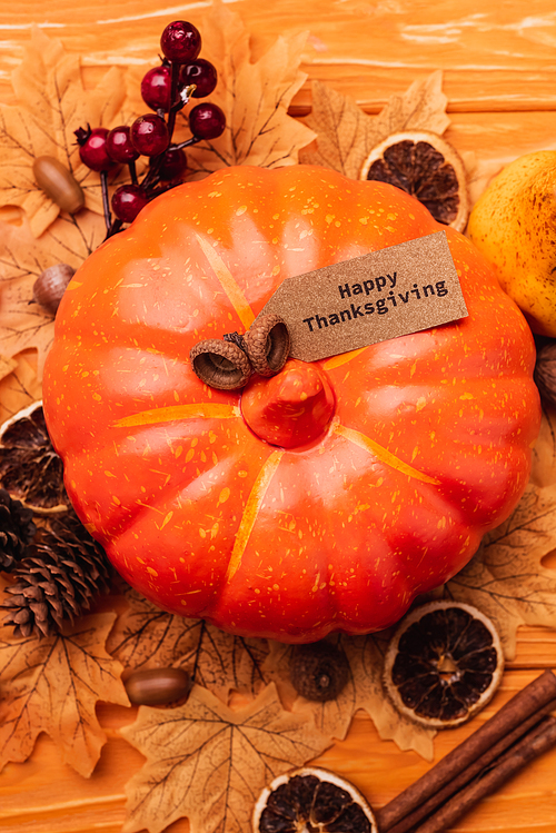 top view of pumpkin with autumnal decoration and happy thanksgiving card on wooden background