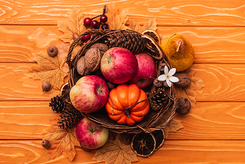 top view of wicker basket with autumnal harvest on wooden background