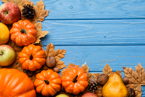 top view of autumnal harvest and foliage on blue wooden background