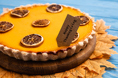 close up view of decorated pumpkin pie with happy thanksgiving card