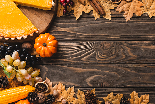 top view of autumnal decoration and pumpkin pie on brown wooden background
