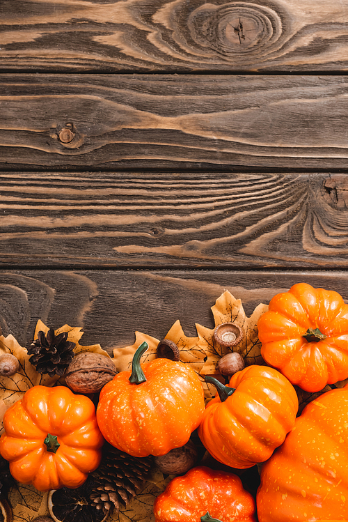 top view of autumnal decoration and pumpkins on brown wooden background