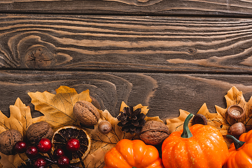 top view of autumnal decoration and pumpkins on brown wooden background