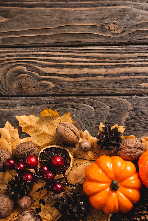 top view of autumnal decoration and pumpkin on brown wooden background
