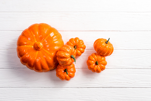 top view of decorative pumpkins on white wooden background