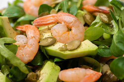 close up view of fresh green salad with pumpkin seeds, shrimps and avocado