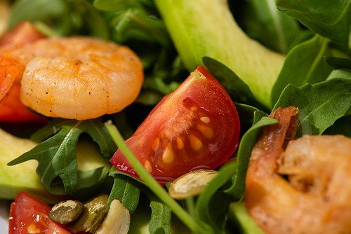 close up view of fresh green salad with pumpkin seeds, cherry tomatoes, shrimps and avocado