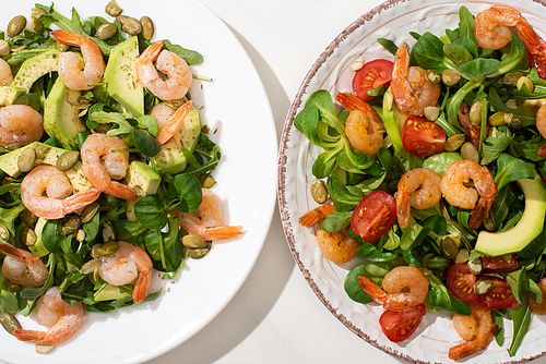 top view of fresh green salad with shrimps and avocado on plates