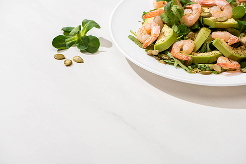 fresh green salad with shrimps and avocado on plate on white background
