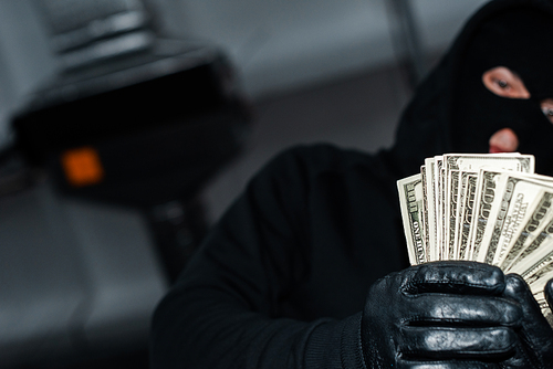 Selective focus of thief in leather gloves holding dollars
