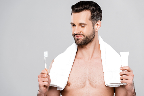 happy bearded man looking at toothbrush isolated on grey