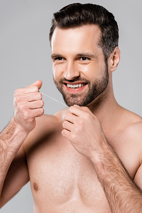 cheerful and muscular man holding dental floss isolated on grey