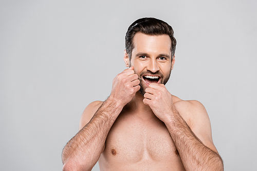 happy and muscular man holding dental floss isolated on grey