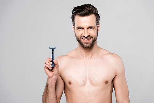 handsome man holding razor while smiling isolated on grey