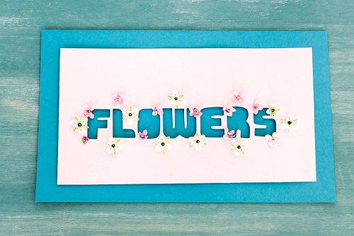top view of greeting card with flowers lettering on blue textured surface,