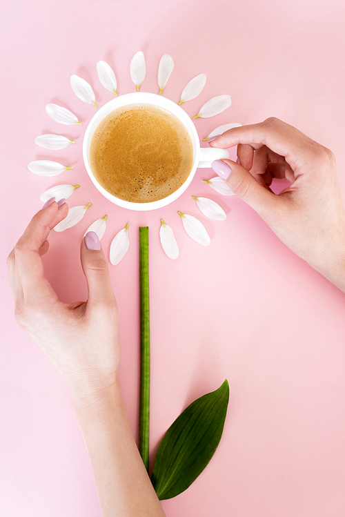 top view of woman touching cup of coffee near white petals on pink, mothers day concept