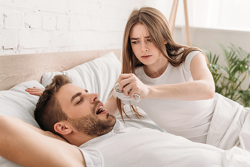 dissatisfied woman holding hanky near face of snoring husband