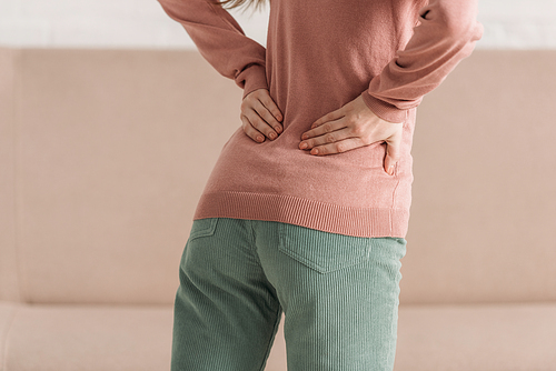 cropped view of woman holding hands on loin while suffering from back pain