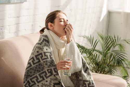 diseased girl, wrapped in blanket, holding glass of water and taking medicine