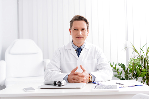 confident ent physician  while sitting at workplace