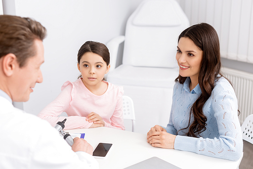 smiling woman with cute daughter on consultation with ent physician