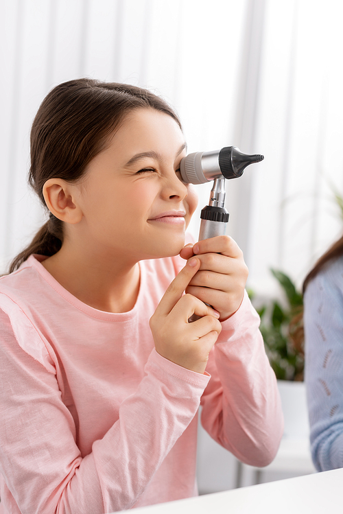 cute child smiling while looking through otoscope in clinic