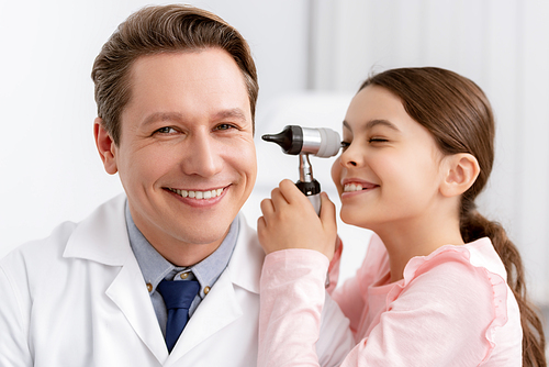 happy kid examining ear of smiling ent physician with otoscope