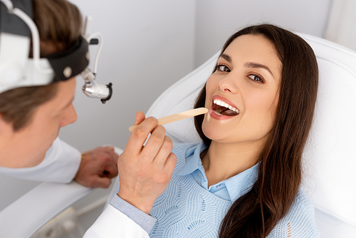 attractive woman  while ent physician holding tongue depressor