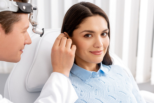 smiling woman  while otolaryngologist examining her ear