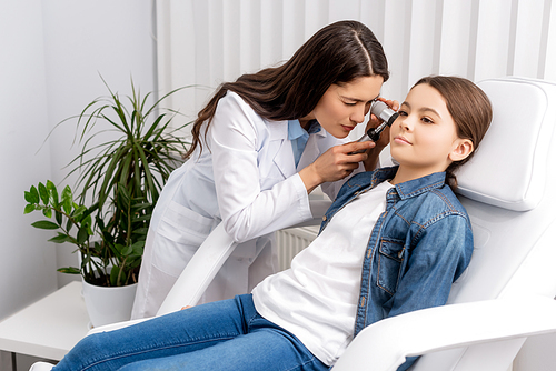 attentive otolaryngologist examining ear of cute child with otoscope