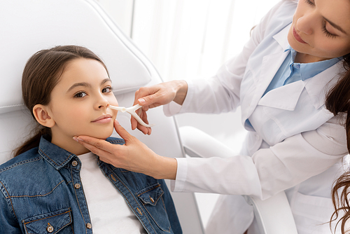 attentive ent physician examining nose of kid with nasal speculum