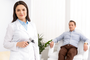 selective focus of attractive ent physician smiling at camera near handsome patient sitting in medical chair