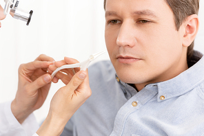 cropped view of ent physician holding nasal speculum near patient