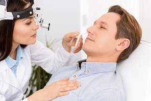 beautiful, attractive otolaryngologist in ent headlight examining nose of patient with nasal speculum