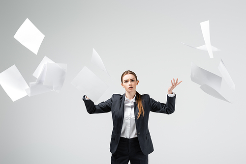 displeased businesswoman in suit throwing papers in air isolated on grey