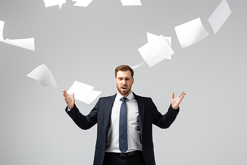 displeased businessman in suit throwing papers in air isolated on grey