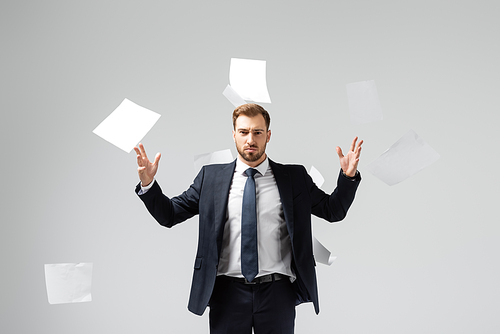 displeased businessman in suit throwing papers in air isolated on grey