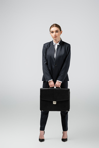 young businesswoman with leather suitcase isolated on grey