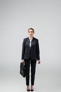 young businesswoman with leather suitcase isolated on grey