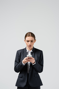 confused young businesswoman using smartphone isolated on grey